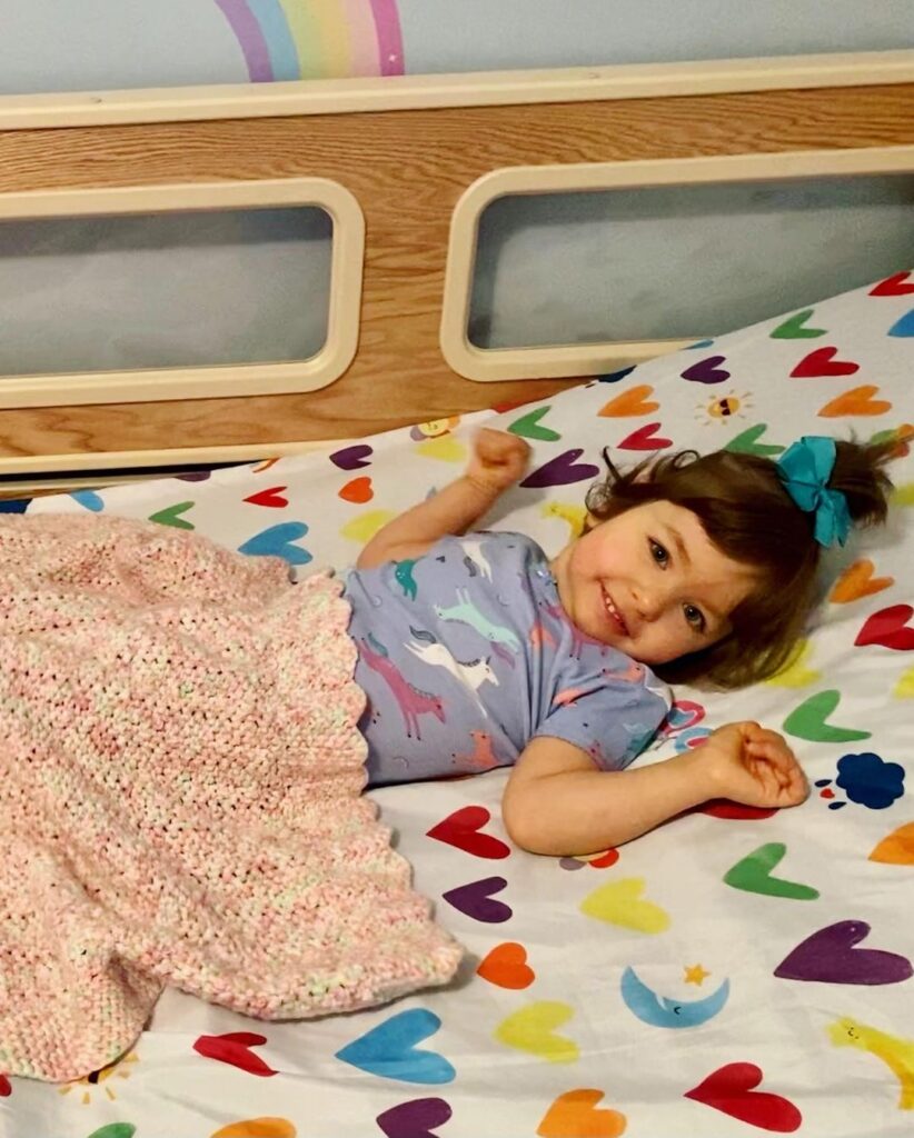 A young girl lying in a SleepSafe bed.