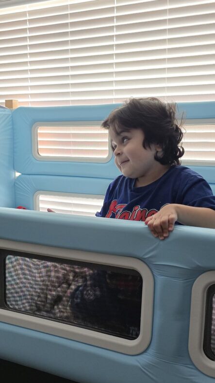 A young boy inside a SleepSafe bed with his hand resting on the bed rail.