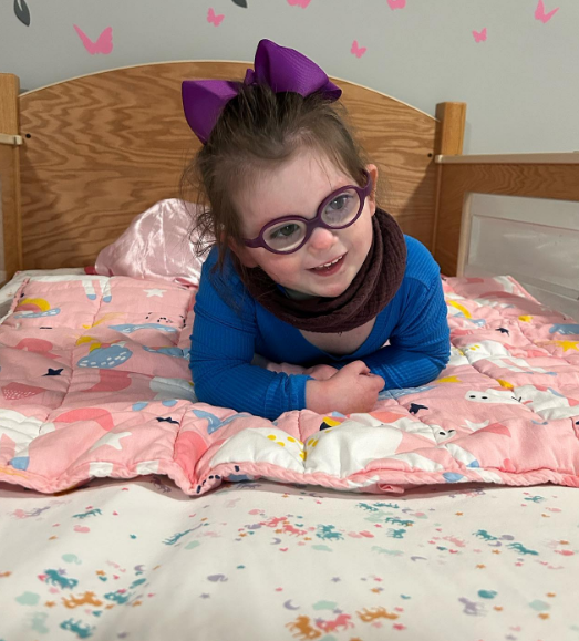 A young girl wearing glasses lying in a SleepSafe bed.