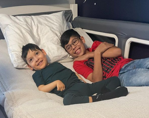 Two boys lying in a SleepSafe bed smiling.