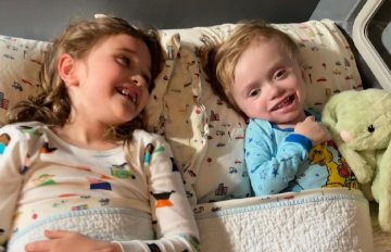 Two children lying side-by-side in their SleepSafe bed.