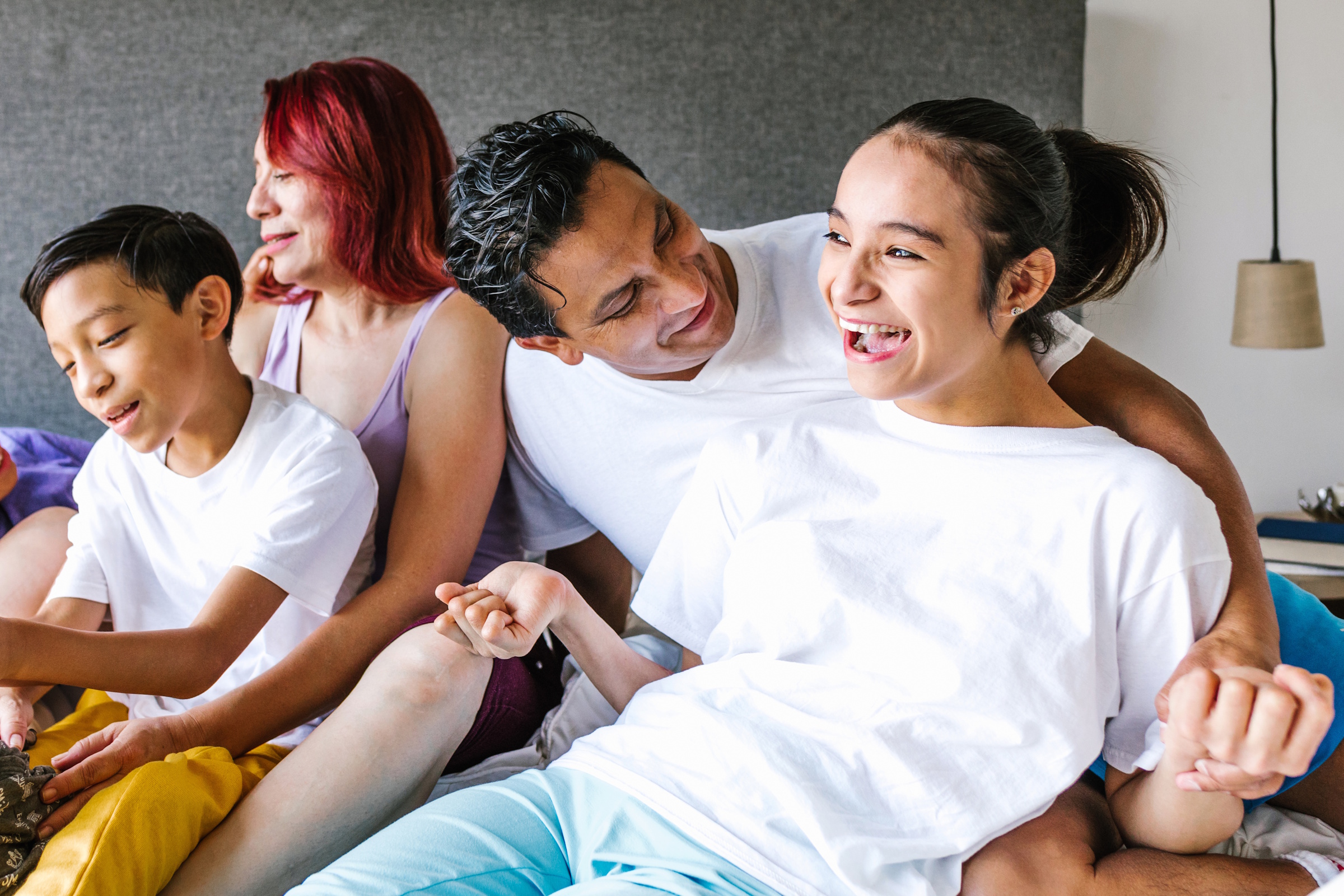 A family of four seated in a close group and laughing.