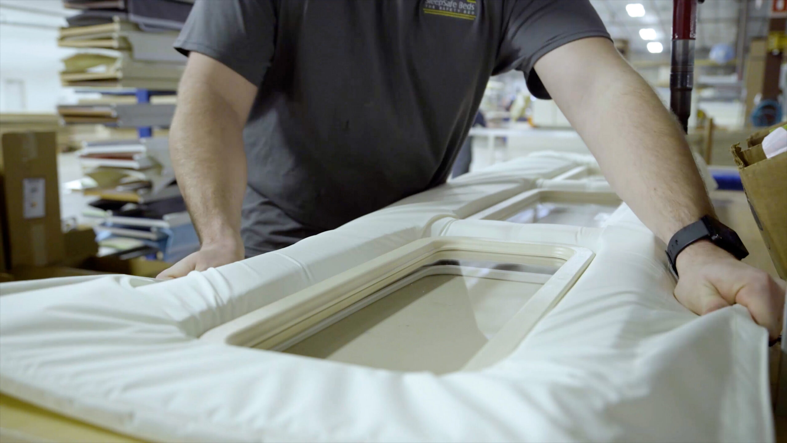 A worker stretching fabric around a bed rail.