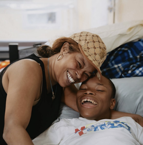 A mom hugging her son who is lying in a SleepSafe bed.