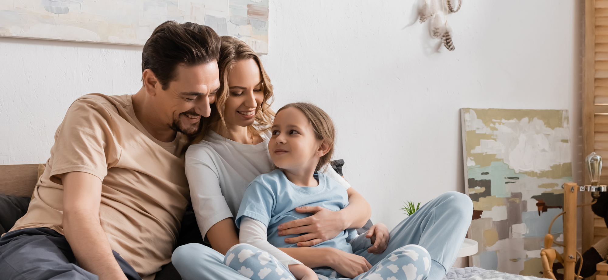 A family of three seated on a couch.