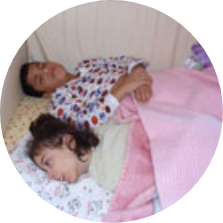 Korii and Ann lying in their SleepSafe bed.