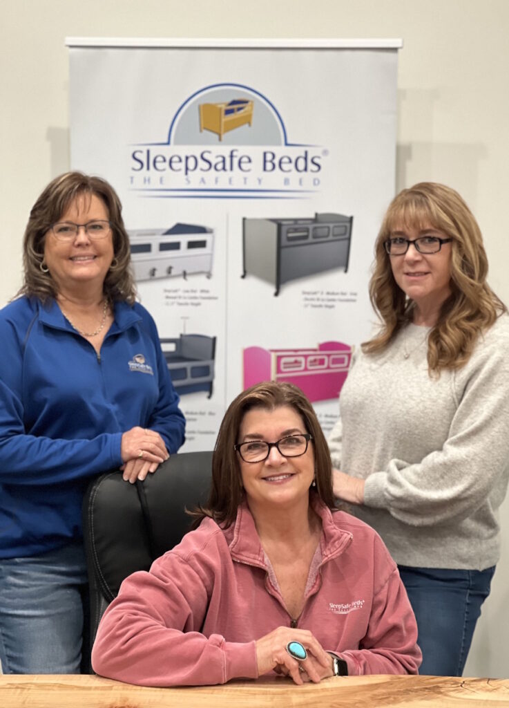 Three women in front of a SleepSafe Beds banner.