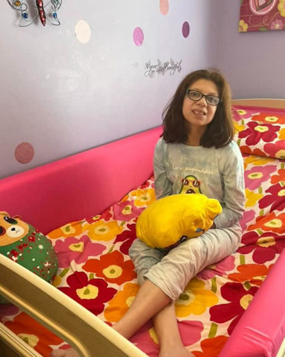 A young girl sitting in a SleepSafe bed.